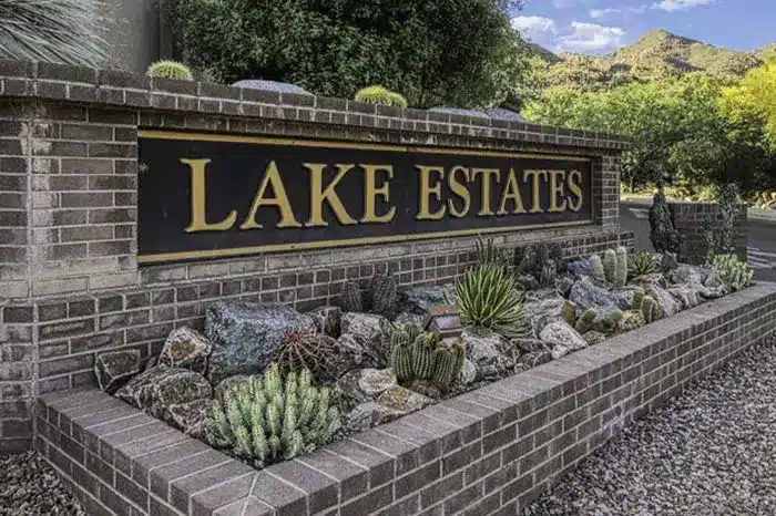 A detailed photo of a brick sign labeled "Lake Estates," featuring a landscaped area with cacti and rocks at its base.